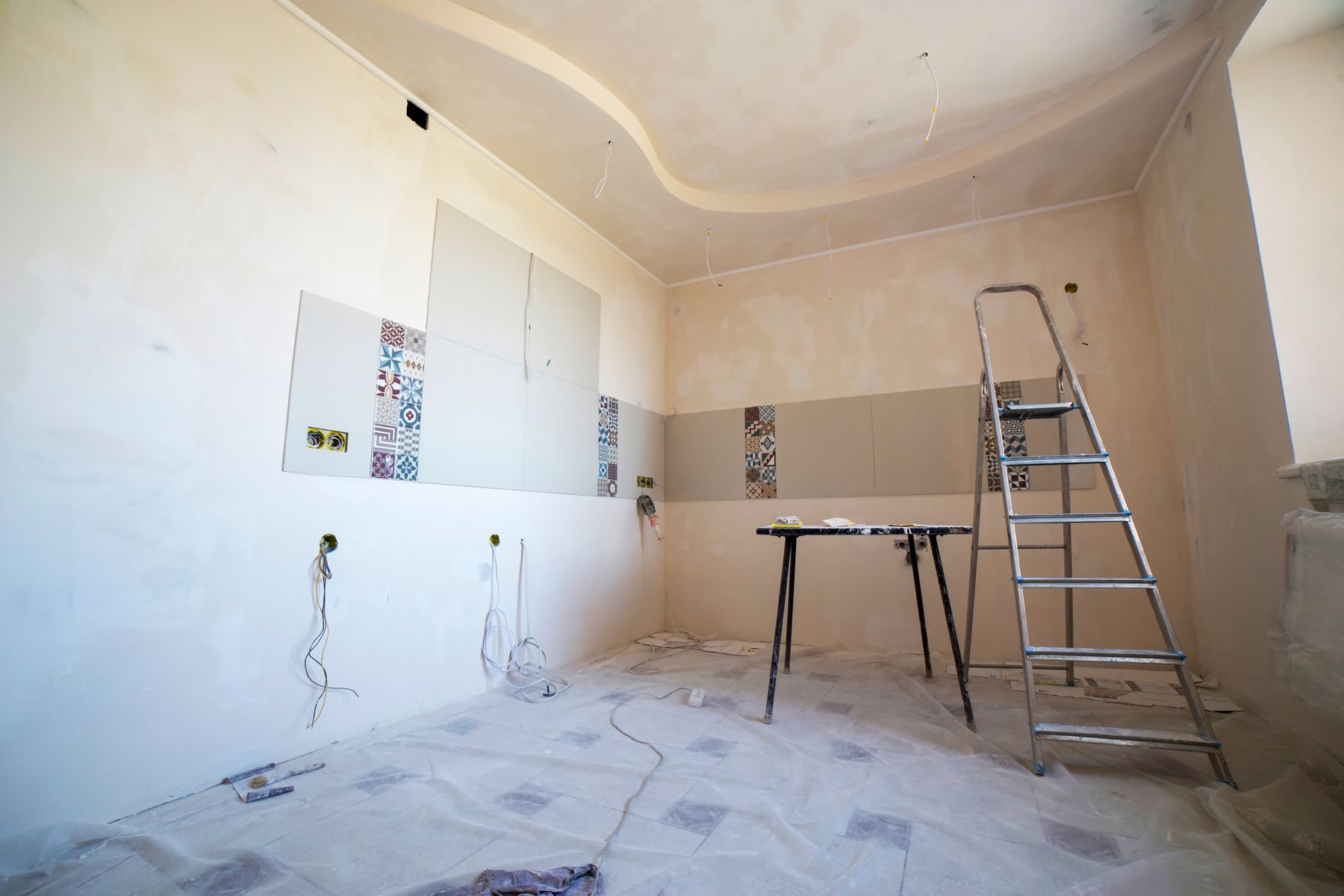 Bedroom as a bare shell: plastered walls, first-fix sockets, a trestle and a ladder.